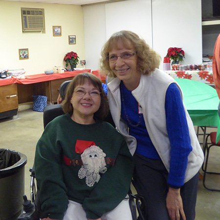 Nancy and Melinda smile for a photo at the Christmas Party.