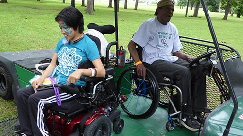 Young woman rolling her powerchair down the ramp of the Green Kart.